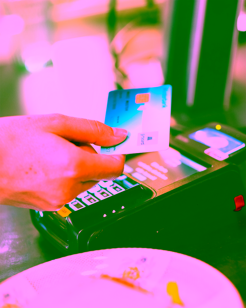 Kartenlesegerät und naher Blick auf eine blaue girocard, die beim Bezahlen an einem Terminal gehalten wird; klare Fokus auf Karte, Umfeld leicht unscharf