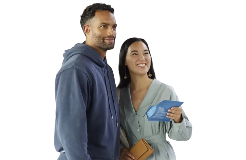 Junges Paar lächelt glücklich und posiert für ein Foto, während die Frau einen blauen Informationsflyer in der Hand hält und der Mann in einem grauen Hoodie gekleidet ist.