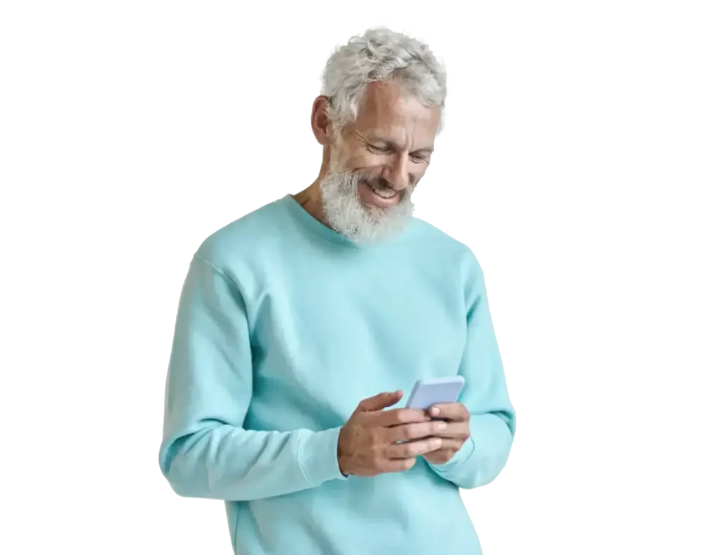Älterer Mann mit grauem Bart und lockigem Haar, der in einem hellblauen Sweatshirt ein Smartphone benutzt und dabei lächelt.