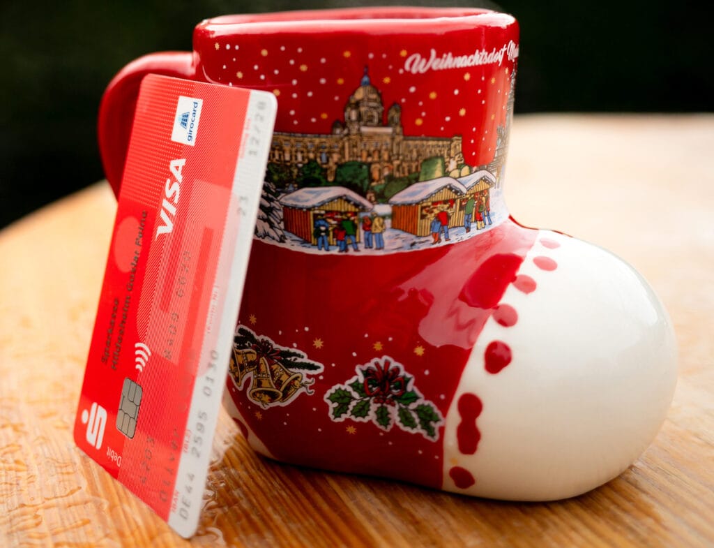 Die girocard lehnt an einer weihnachtlichen Tasse in Form eines roten Stiefels.
