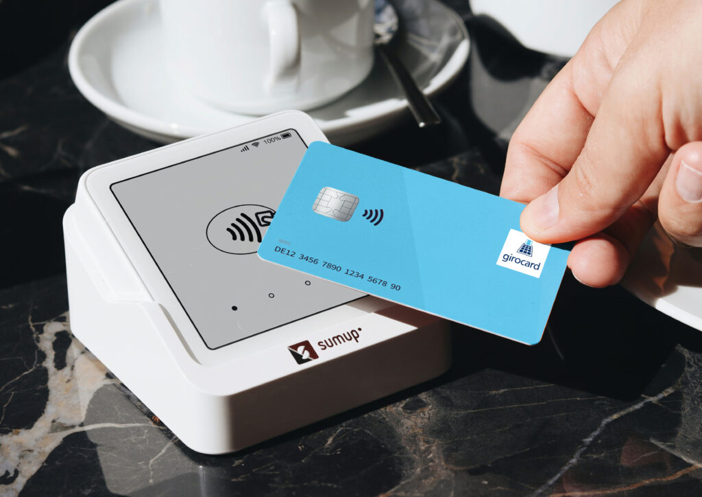 Eine girocard wird an ein Sam-Up-Terminal gehalten, um eine Zahlung zu tätigen.