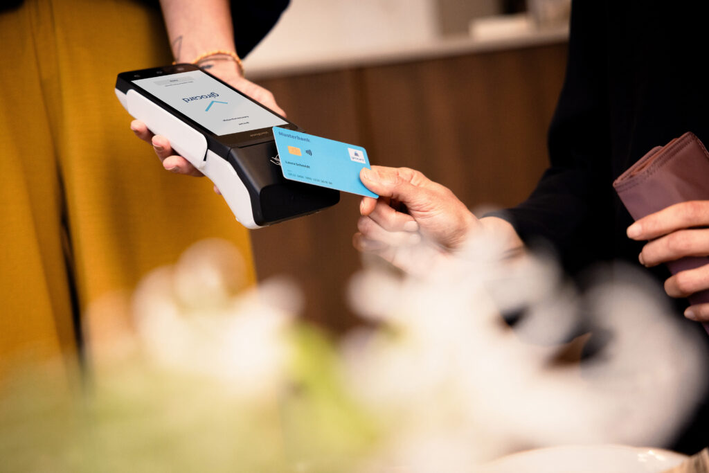 Eine girocard wird an ein Terminal zur kontaktlosen Bezahlung gehalten.