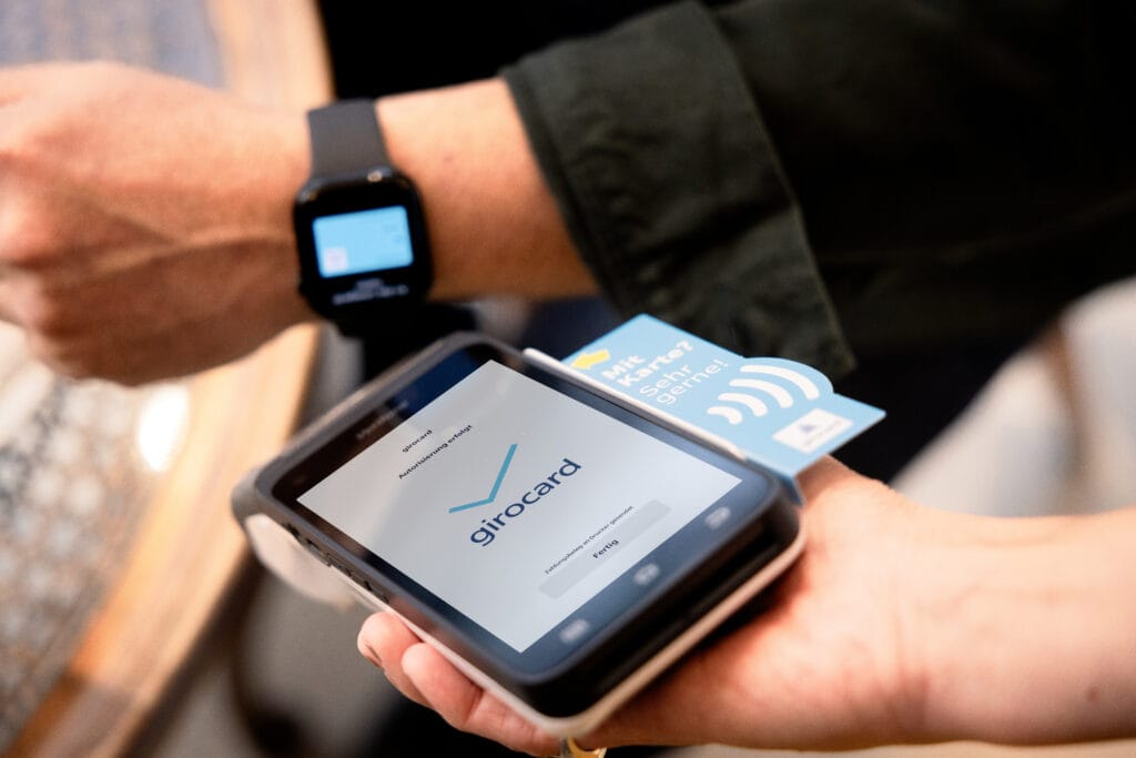 Ein Mann hält seine Smartwatch an ein Smartphone mit Tap-to-pay-Funktion, um zu bezahlen