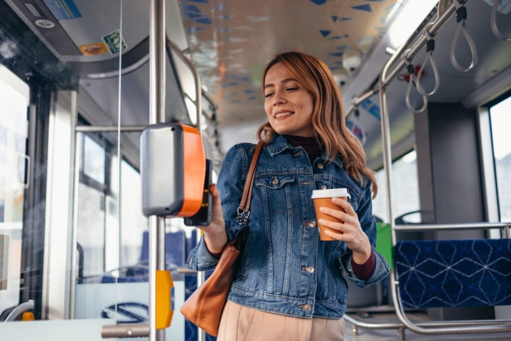 Eine Frau hält im Bus ihr Handy an ein Terminal.