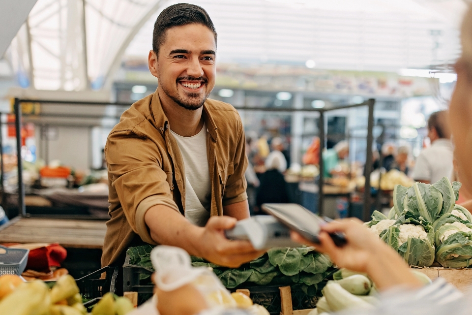Ein Mann zahlt auf dem Wochenmarkt kontaktlos und hält seine girocard ans Terminal.